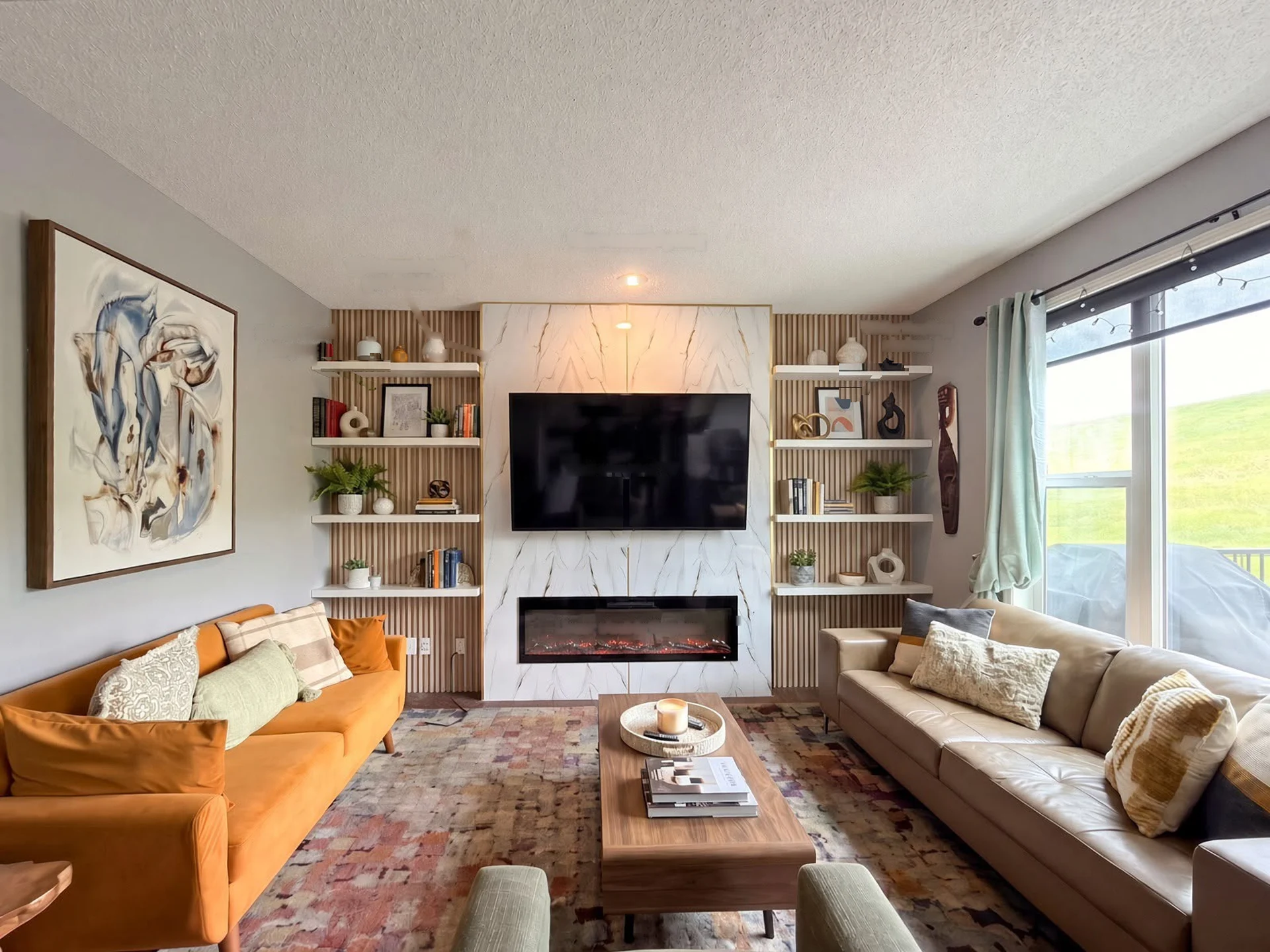 Custom media wall unit with marble feature panel, fluted wood side panels and a linear electric fireplace, built by Met Interiors in Calgary